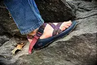 A person wearing the Chacos Z Cloud Sandal standing on a rock