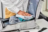 Hand packing clothes in the Matein Travel Backpack 40L