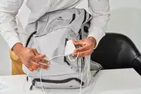 Hands putting a portable charger in a front pocket on the Matein Travel Backpack 40L