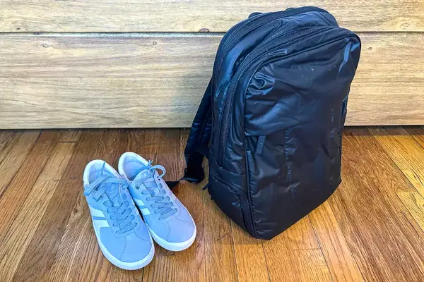 Photo of blue sneakers next to the calpak luka backpack