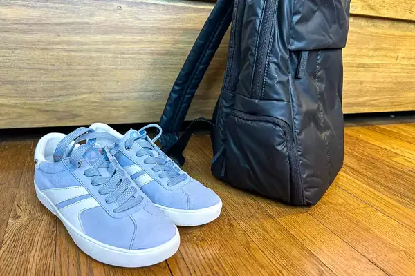 Photo of blue sneakers next to a black backpack