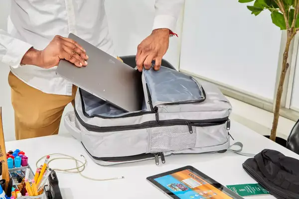 Hands putting a laptop in the Matein Travel Backpack 40L