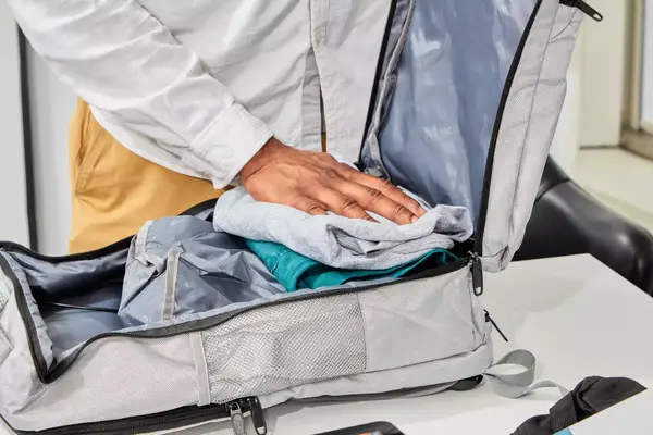 Hand packing clothes in the Matein Travel Backpack 40L