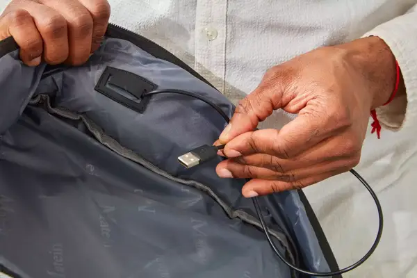 Hand holding a USB cord inside the Matein Travel Backpack 40L