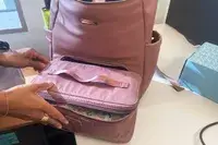 Hands zipping the MinkeeBlue Nichet Backpack 3.0