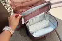 Hand opening the lid of the MinkeeBlue Nichet Backpack 3.0