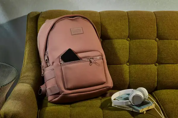 A medium Dagne Dover Dakota Neoprene Backpack sitting on a couch