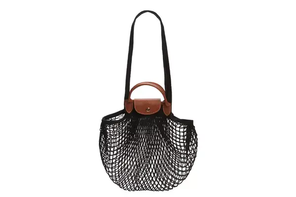 A person holds a Gaiatop Portable Handheld Folding Fan on a sunny beach with the sea in the background