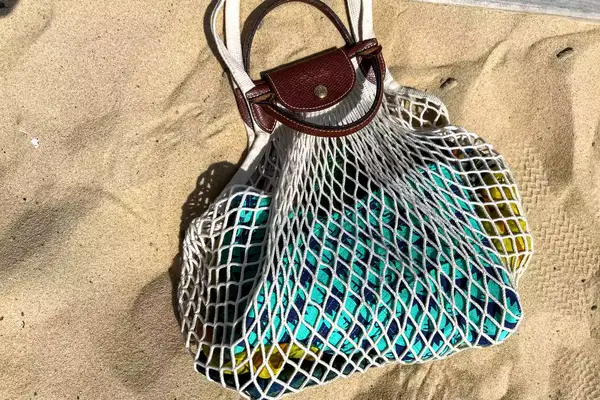 The Longchamp Le Pliage Filet L Mesh Bag on beach sand