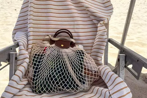 The Longchamp Le Pliage Filet L Mesh Bag on a beach chair