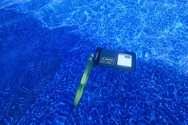 A phone in the Case-Mate Pelican Marine IP68 Waterproof Phone Pouch submerged in a pool