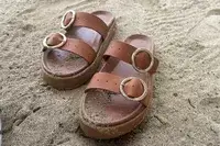 Beek Warbler Leather Platform Platform Leather Slides covered in sand with a sand background