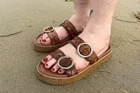 A person wearing the Beek Warbler Leather Platform Platform Leather Slides on the sand