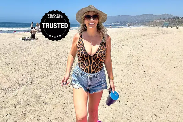 Smiling person with a hat walking on a beach, a badge reading 