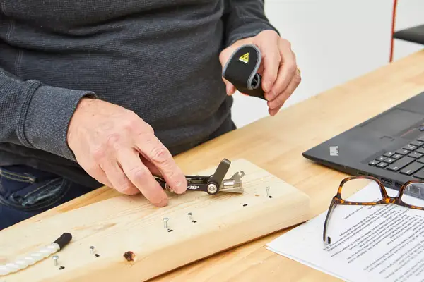 Topeak Mini 18+ Multi-Tool is being used to clip a nail on wooden plank