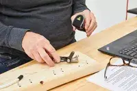 Topeak Mini 18+ Multi-Tool is being used to clip a nail on wooden plank