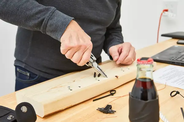 Wetols 21-in-1 Multi-Tool is used to fix a nail on wooden plank