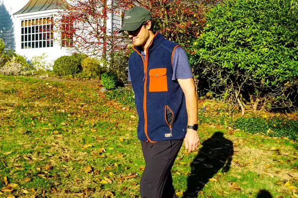 A person walks across a lawn while wearing the Fjallraven Men’s Vardag Pile Fleece Vest