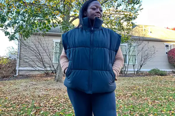 A person stands outside while wearing the Alo Incline Puffer Vest