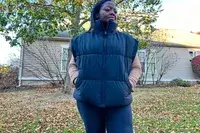 A person stands outside while wearing the Alo Incline Puffer Vest