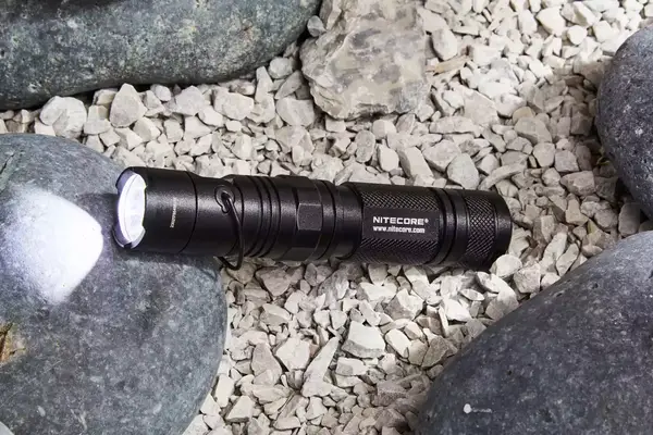 Nitecore MT21C Rechargeable Flashlight in carrying holster displayed on rocks