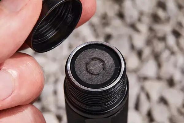 Closeup of fingers holding cap above open Nitecore MT21C Rechargeable Flashlight