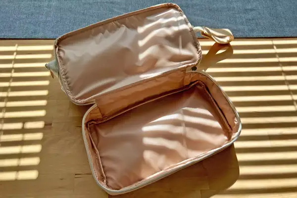 A woman putting makeup in the Away Large Toiletry Bag
