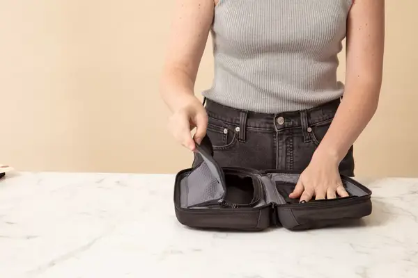 A person zipping the Thule Aion Toiletry Bag closed using a zipper