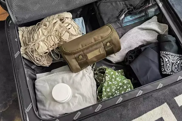 The Dagne Dover Small Seoul Dopp Kit inside a suitcase with clothing