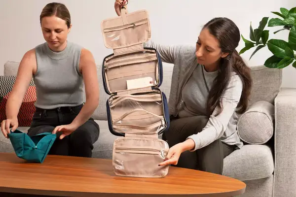 A person holds the Dagne Dover Small Seoul Dopp Kit by the hook