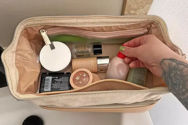 A woman putting makeup in the Away Large Toiletry Bag