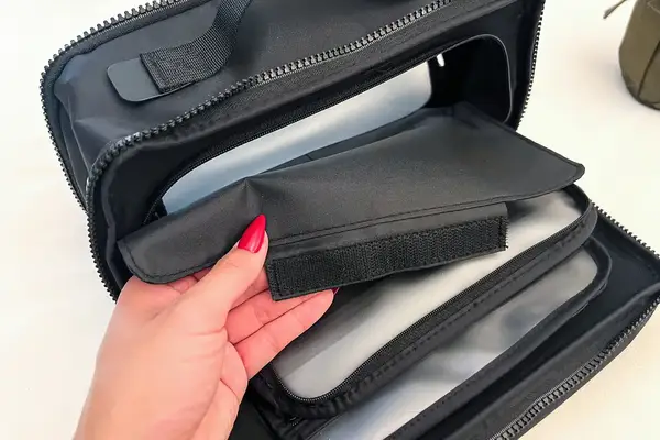 A person holds a velcro cover on the Cincha The Toiletry Bag