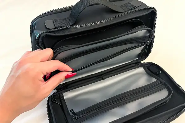 A person holds open a pocket on the Cincha The Toiletry Bag