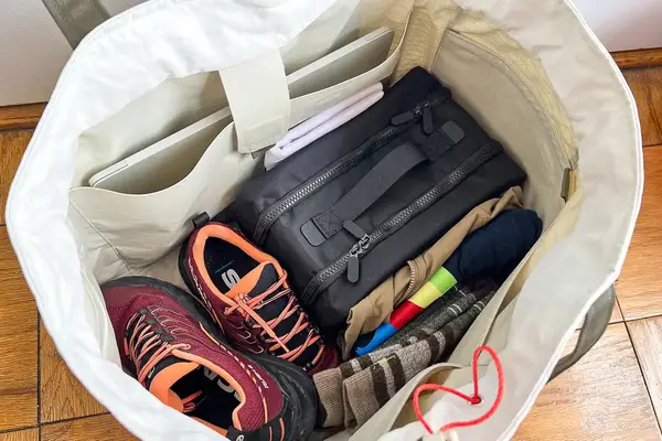 A bag packed with various items including a pair of running shoes and the Cincha The Toiletry Bag