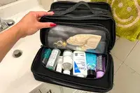 A person shows travel items inside the Cincha The Toiletry Bag