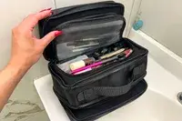 A person holds the top open on the Cincha The Toiletry Bag