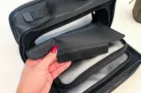 A person holds a velcro cover on the Cincha The Toiletry Bag