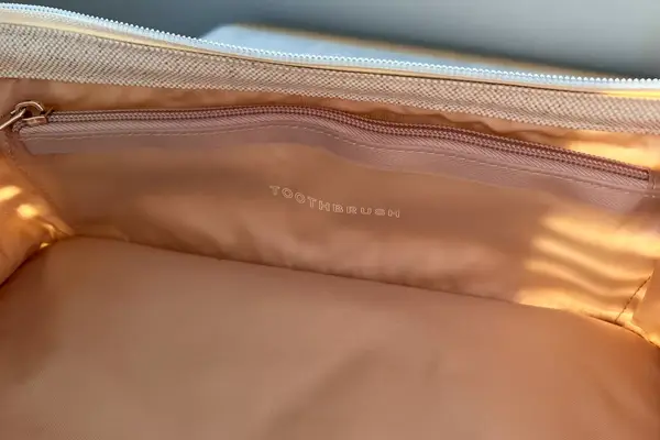  Away Large Toiletry Bag on a dresser with cologne, a mini bottle of shampoo, razor, and lotion around it