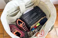 A bag packed with various items including a pair of running shoes and the Cincha The Toiletry Bag