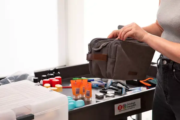 A person places a toiletry item into the Beis The Dopp Kit travel pouch