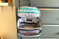 An open BAGSMART Blast 4.5L Hanging Toiletry Bag hangs from a chest of drawers