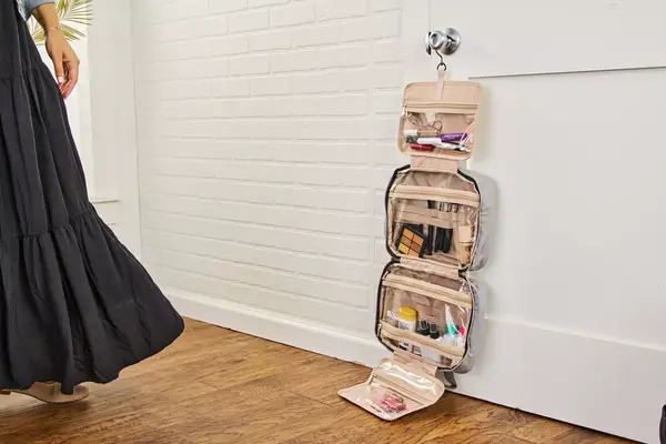 The Bagsmart Toiletry Bag with Hanging Hook hangs from a doorknob