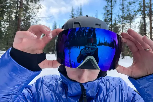 A person putting on the Smith I/O Mag Goggles