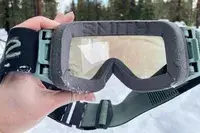A hand holding the Smith I/O Mag Goggles in the snow