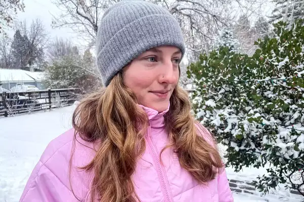 A person wearing the Quince Mongolian Cashmere Ribbed Beanie outdoors in snow