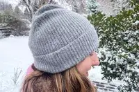Side view of a person wearing the Quince Mongolian Cashmere Ribbed Beanie outdoors in the snow