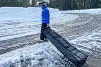 A person rolls the DB Snow Roller Pro 127L over snow