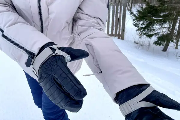 Close up of a person zipping a sleeve pocket on the Aspen Collection Cirque Down Jacket outside