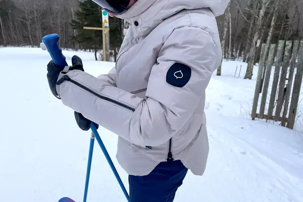 Side view of a person wearing the Aspen Collection Cirque Down Jacket while skiing 