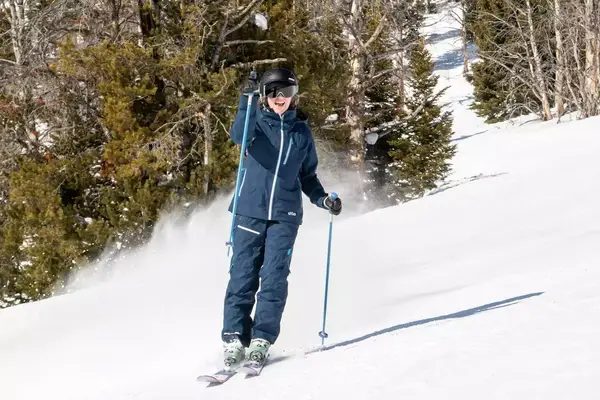 Person skiing with arm raised waiving